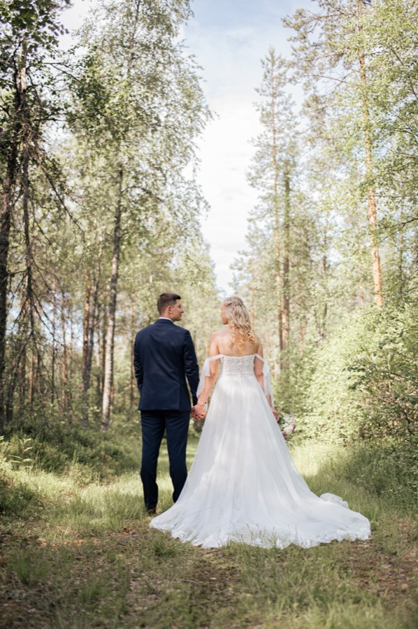 Hääpari kulkee käsikkäin metsässä